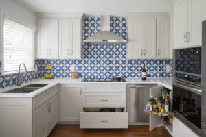 Kitchen renovation with sliding cabinets and blue and white backsplash